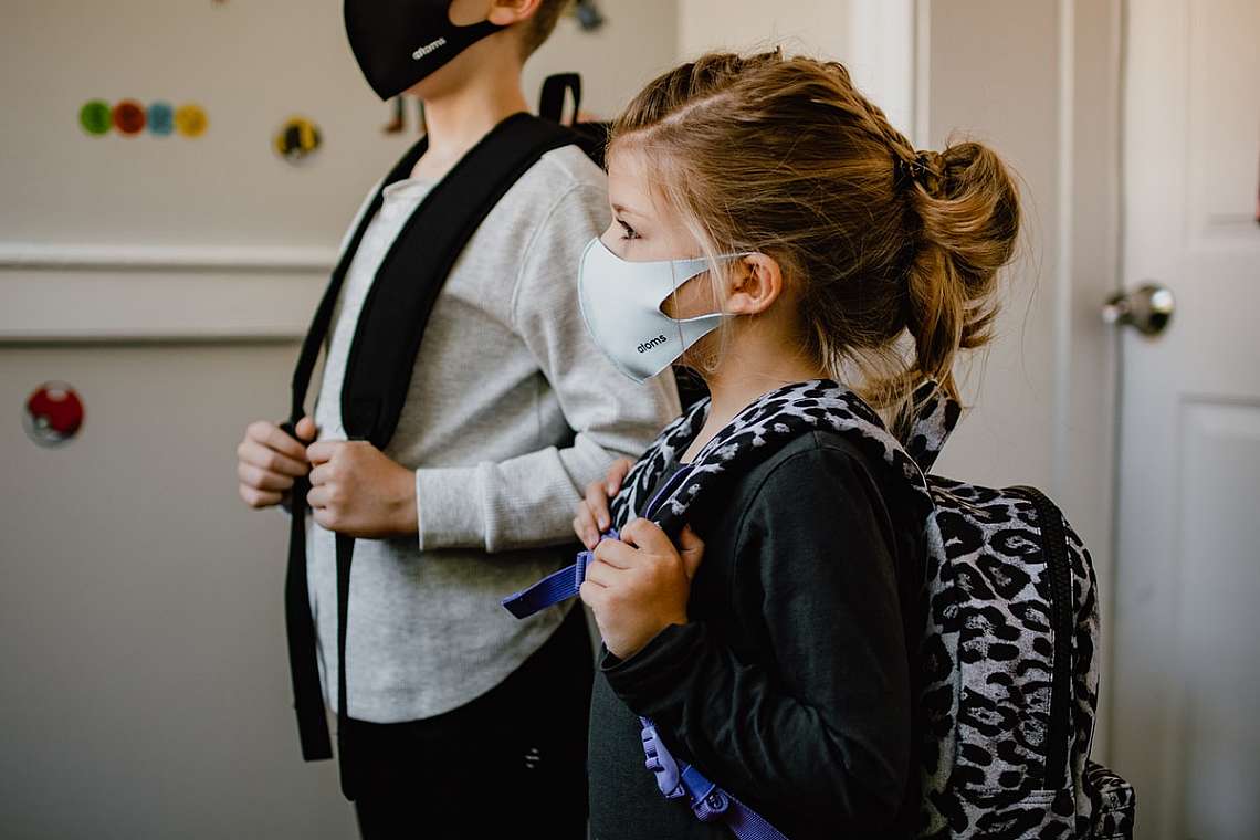 two kids standing side by side wearing masks